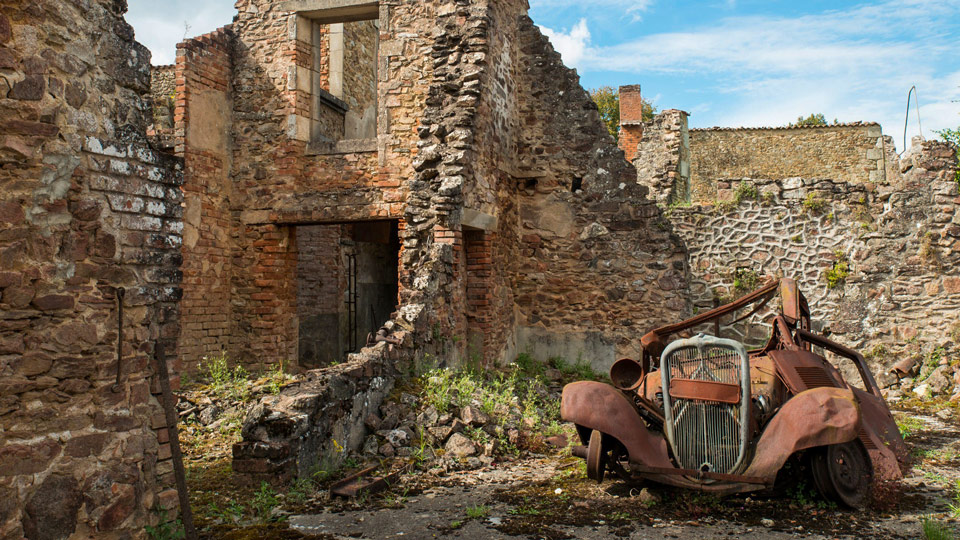 Ein verrostetes Auto in den Ruinen von Oradour-Sur Glane - (Foto: © Denis Prezat / Getty Images)