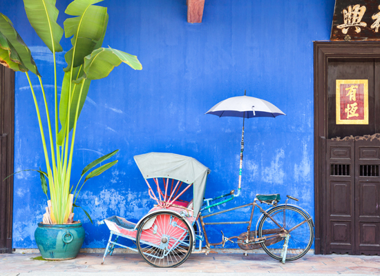Eine Dreirad-Rikscha in der Nähe des "Cheong Fatt Tze Mansion" oder auch "Blue Mansion", einem berühmten orientalischen historischen Gebäude in George Town, Malaysia. © Elena Ermakova / Shutterstock