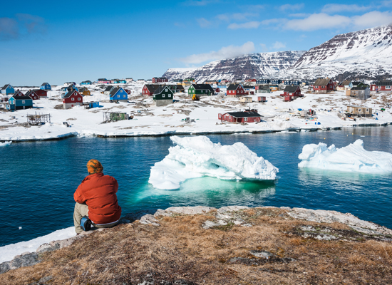 Ein Tourist bewundert den Anblick von Qeqertarsuaq ("große Insel"), einer kleinen Stadt auf Grönland. © Yongyut Kumsri / Shutterstock