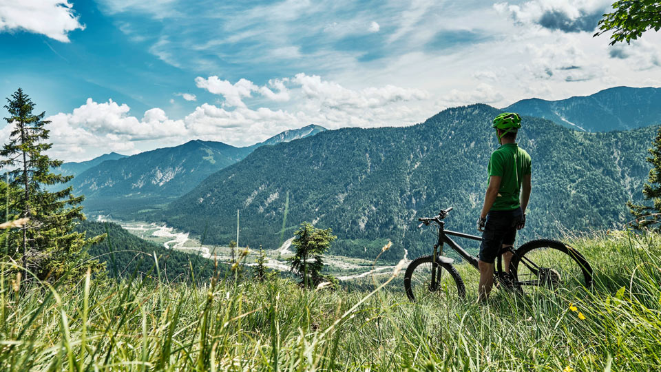 Ein zufriedener Mountainbiker blickt von den Bergen in das Isar-Tal hinab - (Foto: © Westend61 / Getty Images)