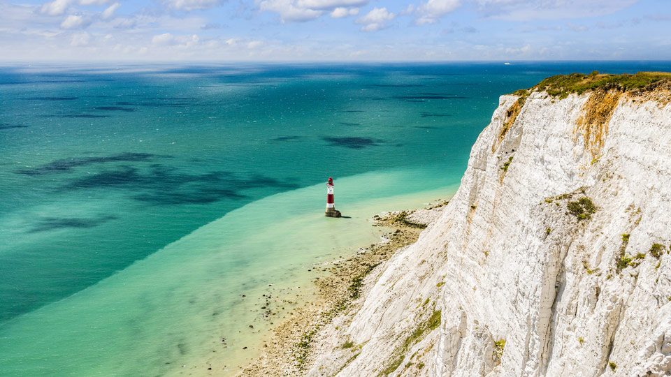 Der berühmte rot-weiß gestreifte Leuchtturm am Fuße der Kreidefelsen in Beachy Head, Sussex - (Foto: © travellight/Shutterstock)