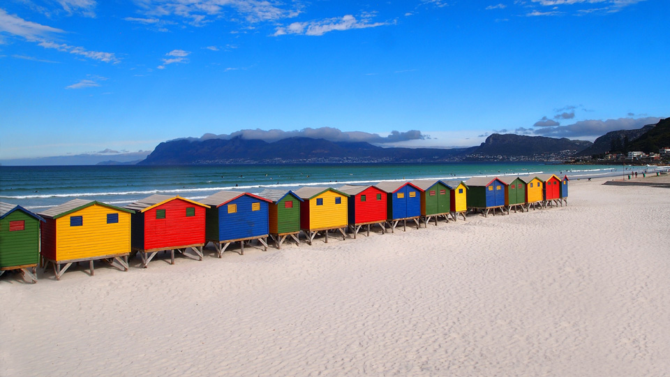 Sie blinzeln lustig in der Sonne - die farbenfrohen, hölzernen Hütten am Sun Beach, Kapstadt Muizenberg - (Foto: ©Ariadna22822/Shutterstock)