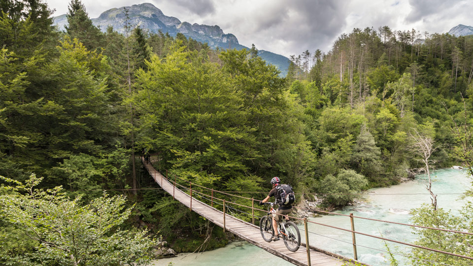 Mit dem Mountainbike über die Hängebrücke den Fluss Soča in den Julischen Alpen von Nordslowenien überqueren - (Foto: ©Saro17/Getty Images)