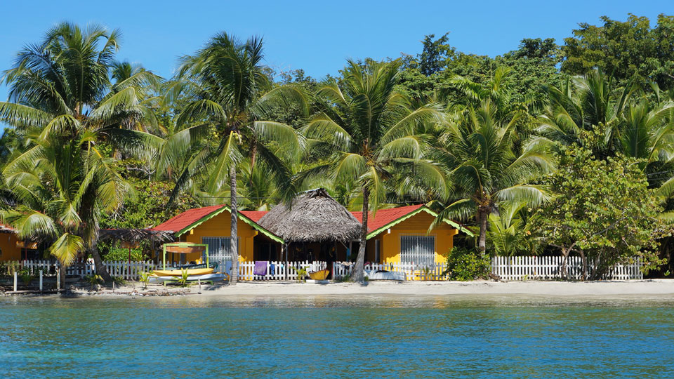 Bunt gewürfelt stehen die Häuschen am schneeweißen Strand von Panamas Bocas del Toro - (Foto: © Damocean / Getty Images)