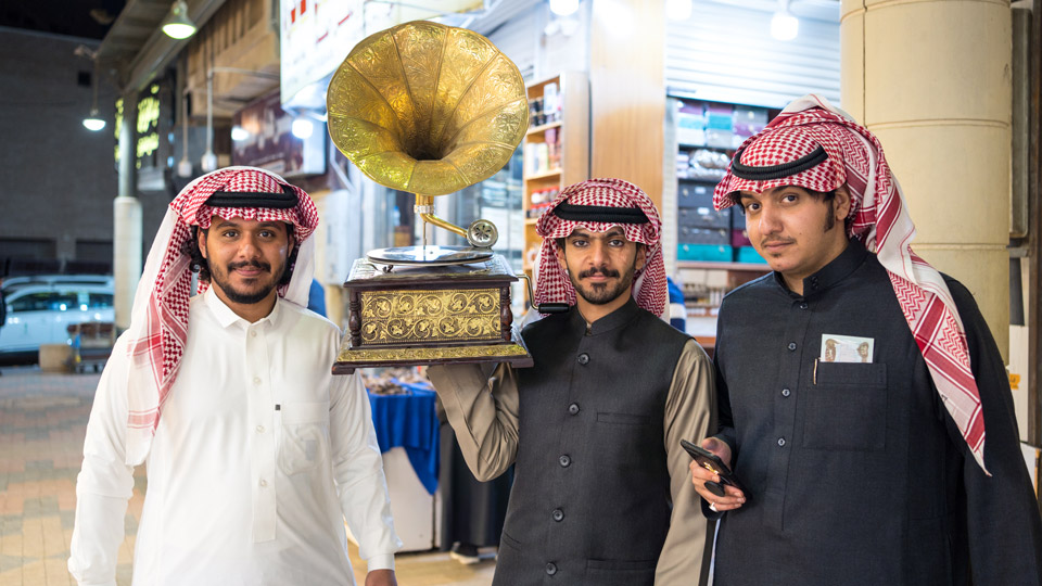 Junge saudische Männer in traditioneller Kleidung und der Ghutra auf dem Kopf mit ihrer “Beute” vom Ausflug in Riads Souks - (Foto: ©Juan Alberto Casado/Shutterstock)