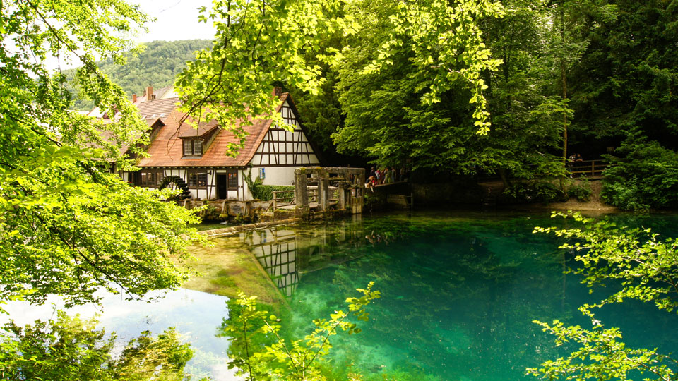 Die  historische Hammermühle spiegelt sich im blau-türkisfarbenen Wasser am "Blautopf" in Blaubeuren wider - (Foto: © ThePhotoFab / Shutterstock)