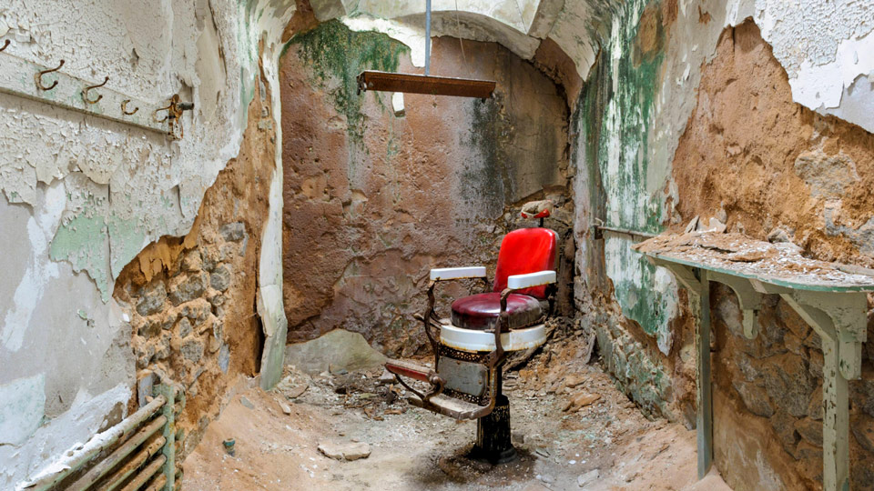 Ein Friseurstuhl in einer verlassenen Gefängniszelle im Eastern State Penitentiary - (Foto: © catnap72 / Getty Images)