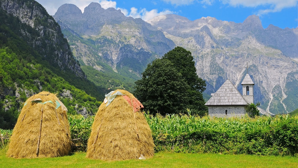 Idyllische Kulisse: Die Heuhaufen im Tal um das malerische Örtchen Theth werden von den hohen Gipfeln bewacht - (Foto: ©Przemyslaw Wasilewski/Shutterstock)